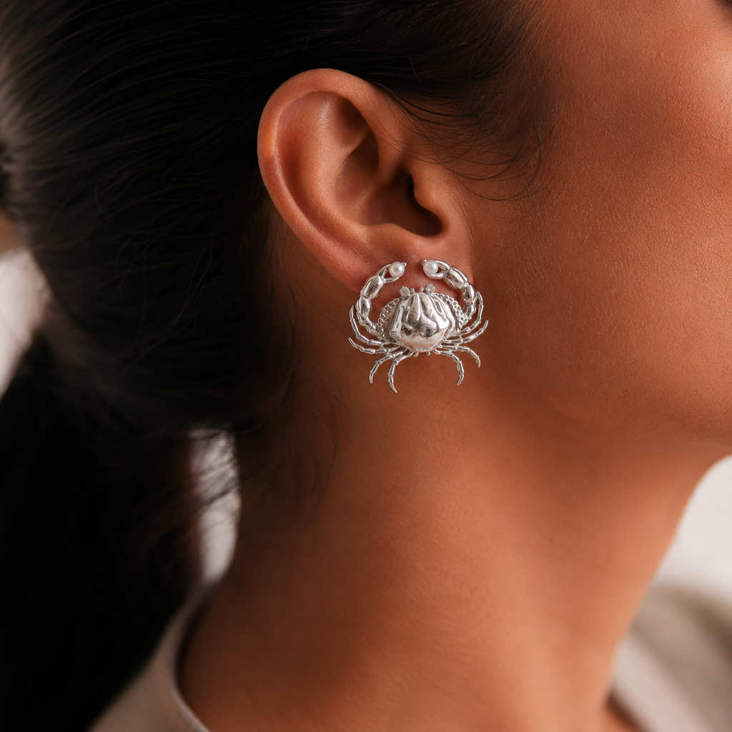 Silver crab-shaped earring worn by a women with dark hair.